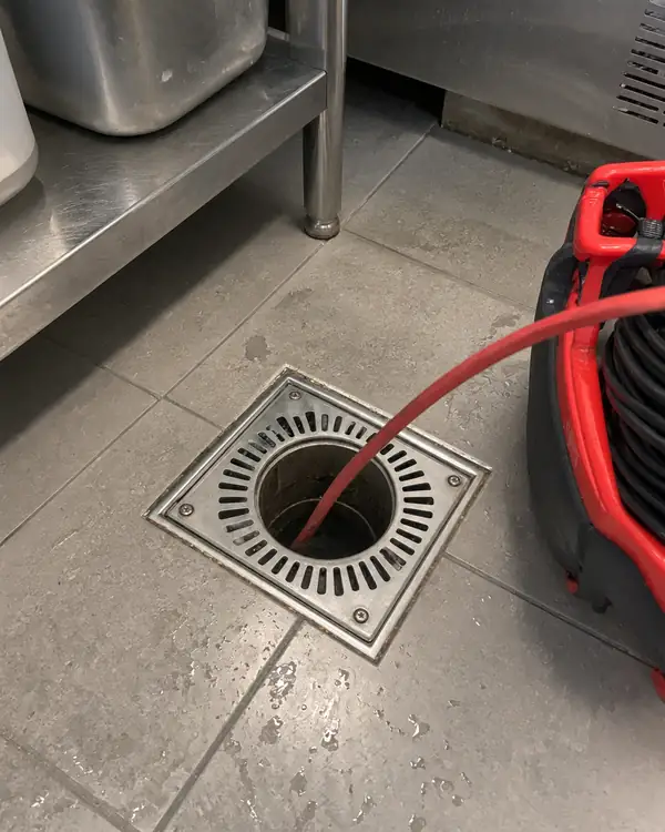 Câble de caméra d'inspection introduit dans un siphon de sol de cuisine professionnelle