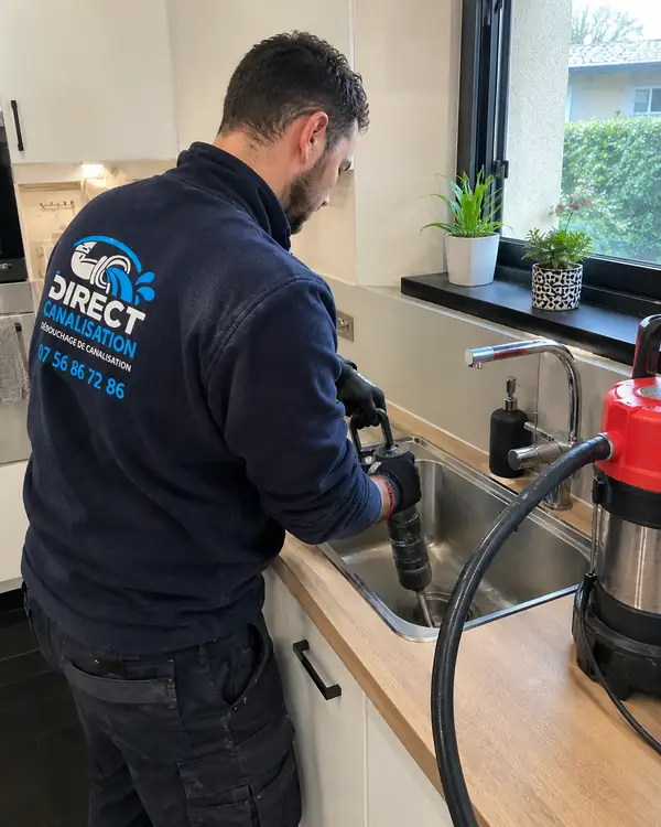 Technicien Direct Canalisation utilisant une pompe à pression sur l'évier d'une cuisine